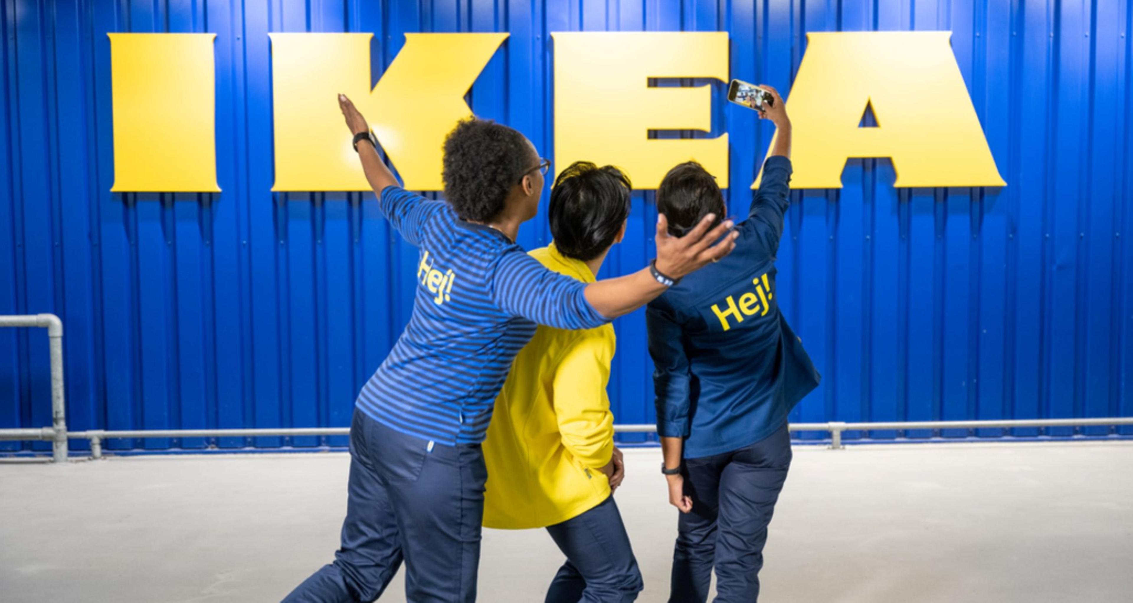 Employees taking a selfie in front of an IKEA sign.