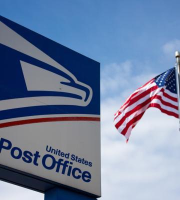 USPS sign next to a flag.