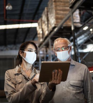 Two professionals wearing masks, looking at an iPad.