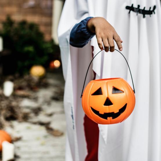 A kid holding a jack-o'-lantern.