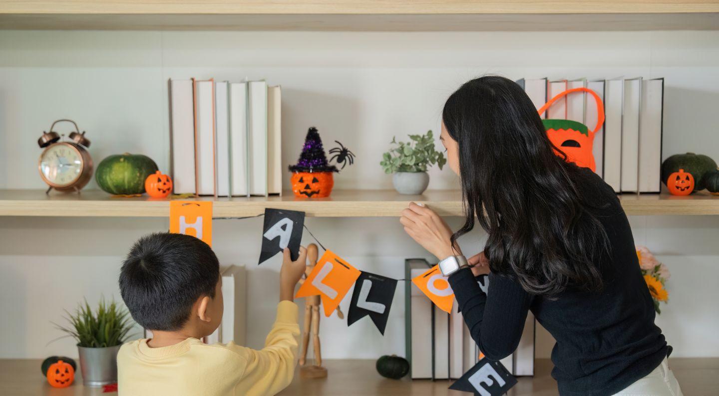 A mother and child decorating for Halloween.