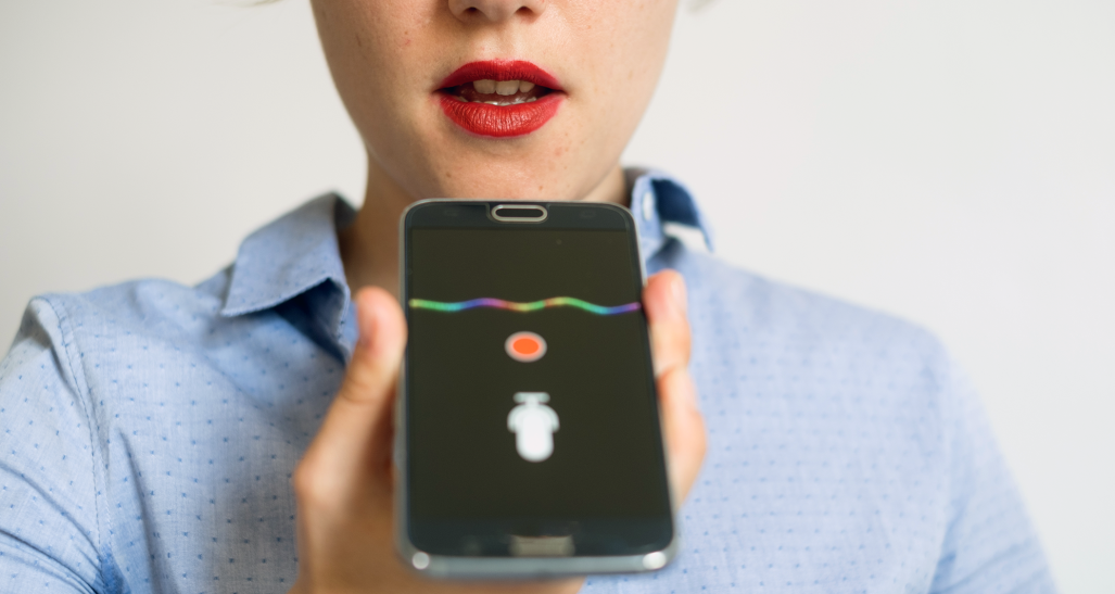 female speaking into her device's using voice assistance technology