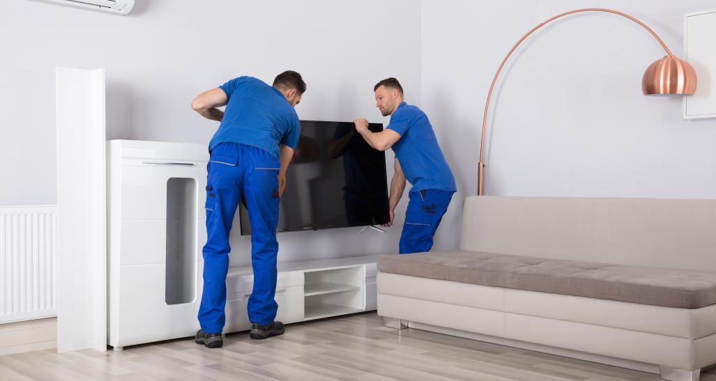 Two men delivering furniture to a living room