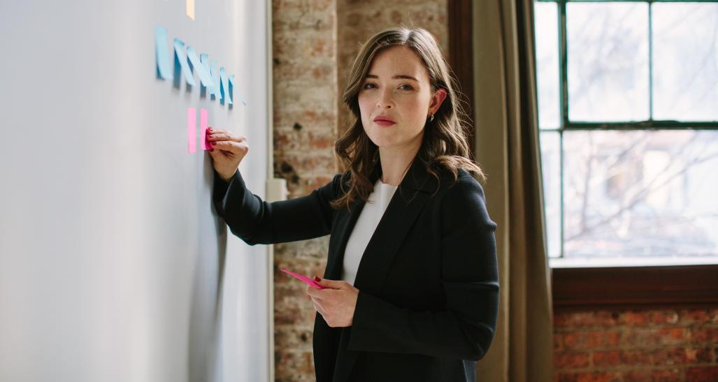 MM.LaFleur model wearing suit writing on whiteboard