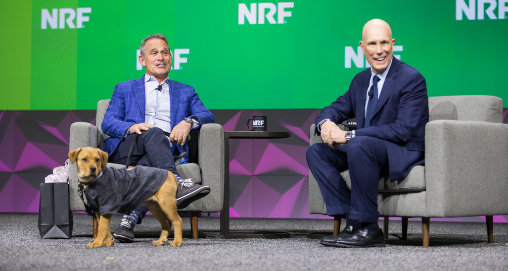 Petco CEO Ron Coughlin on the keynote stage at NRF 2023: Retail's Big Show with NRF's Matt Shay and a dog