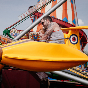 a father and his son enjoy an amusement ride together