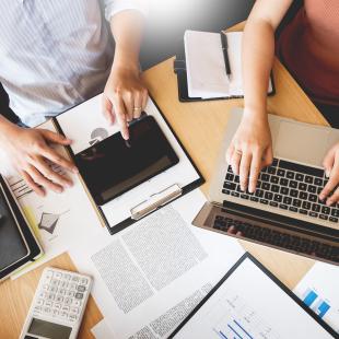 Hands pointing at tech devices workstation