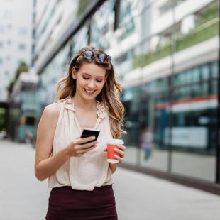 A woman looks at her phone on a city street