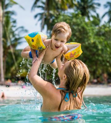 Mom plays with little boy in the water on vacation