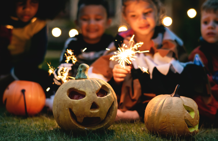 Kids with fireworks and Halloween carved pumpkins